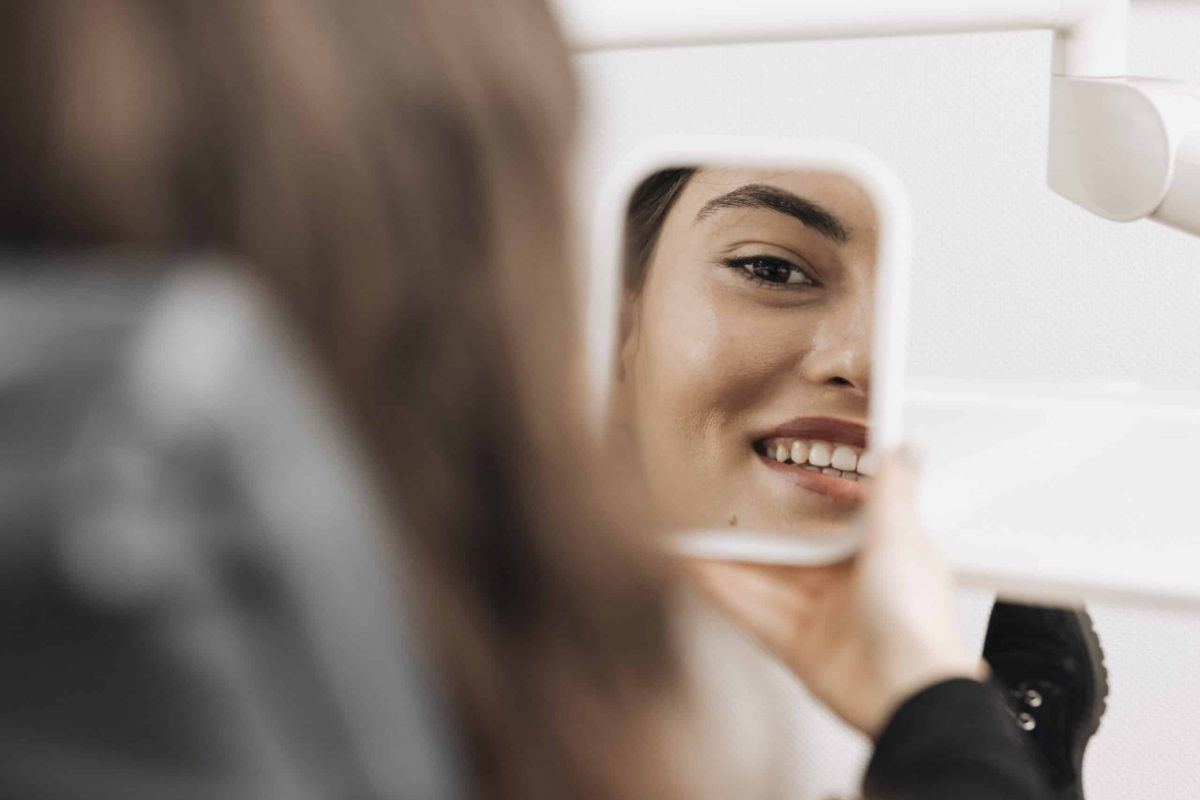 Patientin betrachtet sich im Spiegel in der Zahnarztpraxis Dr. Stefan Bernuth in Würzburg